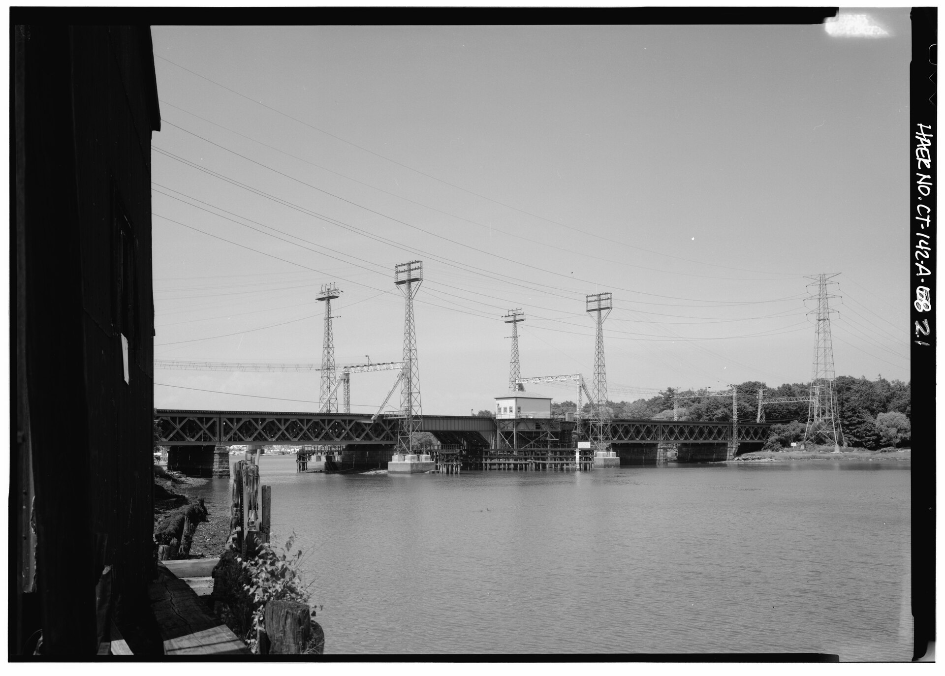 VIEW OF MIANUS RIVER RAILROAD BRIDGE LOOKING NORTHEAST FROM THE REMAINS OF THE COS COB POWER PLANT COALING DOCK. THE BRIDGE IS A ROLLING LIFT BASCULE TYPE BUILT IN 1894-1895. HAER CONN,1-GREWI,15A-21 · Jet Lowe / Historic American Engineering Record / Public domain