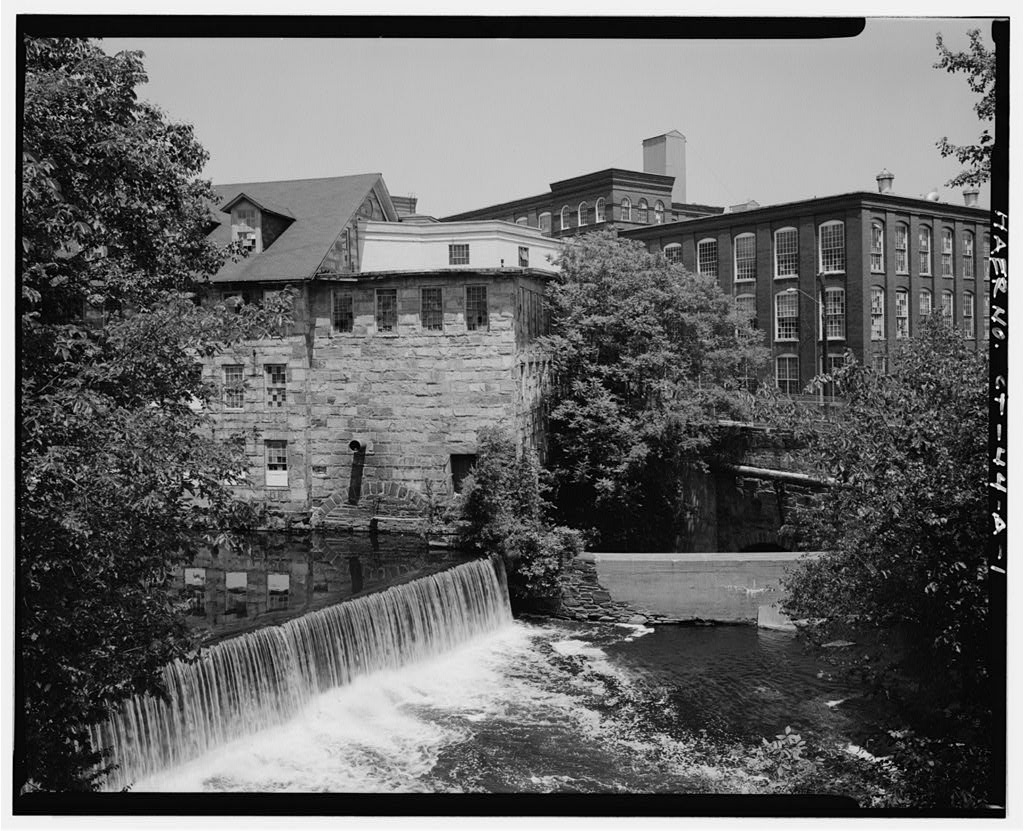View northeast of wheelhouse area, tailrace (center), and dam; mill no. 5 (haer no. ct-44-b) and bridge at right — June 1988